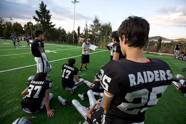 In this Nov. 5 file photo, Raiders youth squad players listen to their coach at halftime of game against the Buhos on the outskirts of Mexico City.