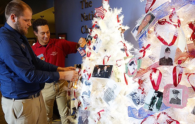Holiday trees devoted to veterans will grace the lobby of the National Churchill Museum at Westminster College through the end of the year. Tyler Oberlag, left, manager of guest services and museum operations, and Manzell Payne, front desk attendant, are holding two ornaments available at the museum's gift shop. 