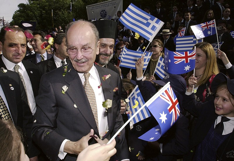 In this photo taken June 7, 2002, the then President of Greece Constantine Stephanopoulos is greeted by school children, waving Greek and Australian flags and throwing flower petals, as he arrives at the Greek Orthodox Archdiocese in Sydney. Greece's official Athens News Agency says Stephanopoulos has died, Sunday, Nov. 20, 2016, at the age of 90, after he entered hospital Thursday with pneumonia and his condition deteriorated rapidly.