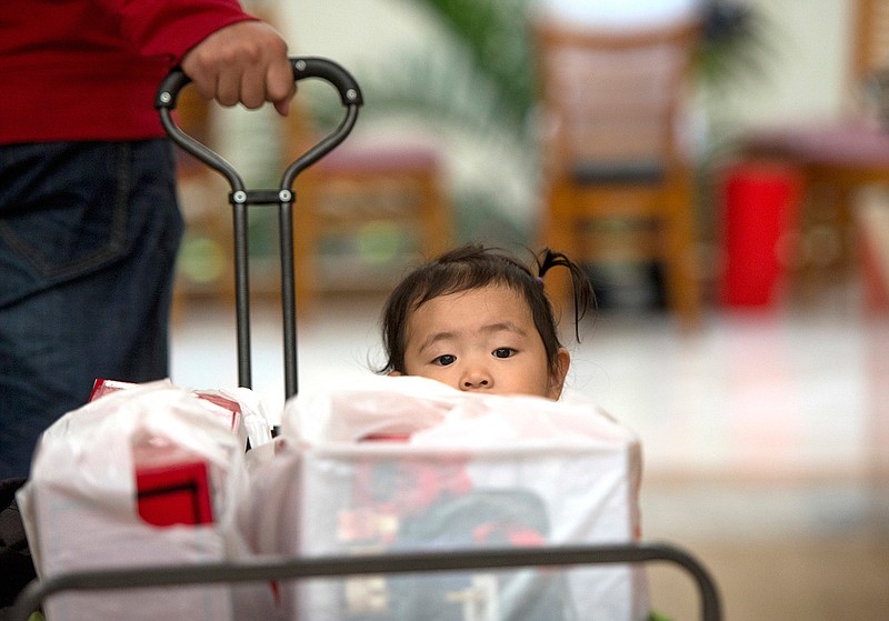 Liang Giang Ying sits in a wagon full of packages as her father pulls her through South Coast Plaza in Costa Mesa, Calif., on Black Friday, Nov. 25, 2016. Stores are trying to better cater to savvier shoppers, who are splitting their spending back and forth online and in stores. That was apparent on Black Friday, the day after Thanksgiving, as shoppers were careful about what deals they'd jump at and retailers pushed different ways to connect with customers.