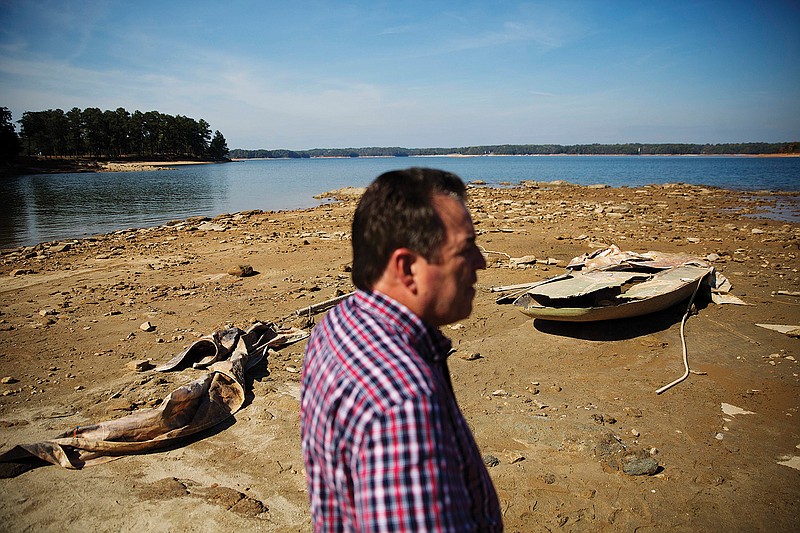 In this Wednesday, Oct. 26, 2016, file photo, a sunken boat is exposed by receding water levels on Lake Lanier as U.S. Army Corps of Engineers Natural Resources Manager Nick Baggett looks on in Flowery Branch, Ga. Though water shortages have yet to drastically change most people's lifestyles, southerners are beginning to realize that they'll need to save their drinking supplies with no end in sight to an eight-month drought. Already, watering lawns and washing cars is restricted in some parts of the South, and more severe water limits loom if long-range forecasts of below-normal rain hold true through the rest of 2016. 