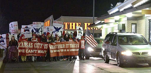 Protesters march around the McDonald's restaurant in the 3200 block of Main Street, early Tuesday, Nov. 29, 2016, in Kansas City, Mo., as part of a national day of protest organized by Fight for $15 and United We Stand movements, seeking higher hourly wages, including for workers at fast-food restaurants and airports. (John Sleezer/The Kansas City Star via AP)