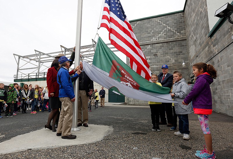 In this Nov. 12, 2015, file photo, fourth grade students from White Bluffs Elementary School help local historians and politicians raise the National Parks Service flag for the first time at Hanford's B Reactor, near Richland, Wash. The new Manhattan Project National Historical Park at Hanford is a year old and proving to be quite popular. About 13,000 people visited the park in its first year, despite its relatively remote location in southeastern Washington, far from the state's major population centers. 