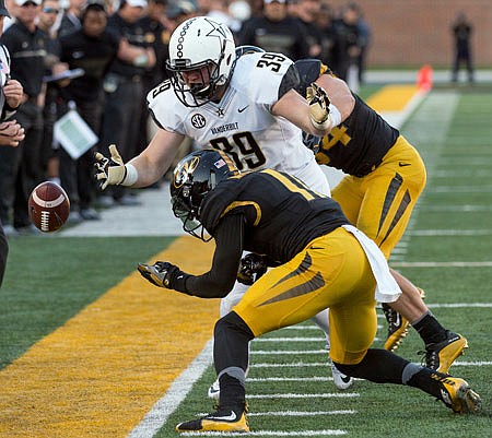 Missouri teammates Joey Burkett (back) and Aarion Penton combine to knock the ball out of the hands of Vanderbilt's Bailey McElwain during a game last month at Faurot Field.