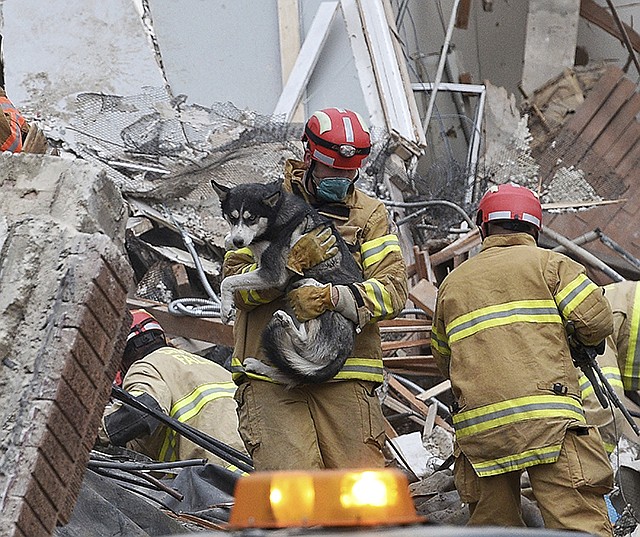 Emergency crews rescue a dog from a building collapse Friday in downtown Sioux Falls. Two people were trapped inside the building, which was undergoing construction at the time of the collapse. A fire official says rescue workers are concerned about debris shifting as they try to free the people.