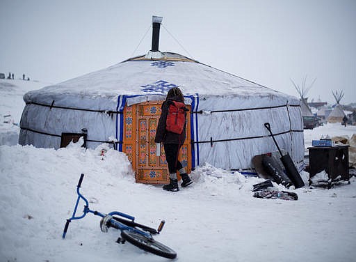 In this Thursday, Dec. 1, 2016 photo, a student walks into the school at the Oceti Sakowin camp where people have gathered to protest the Dakota Access pipeline near Cannon Ball, N.D. The school teaches on average 20 students a day in the traditional Lakota curriculum as well as math, reading and writing. 