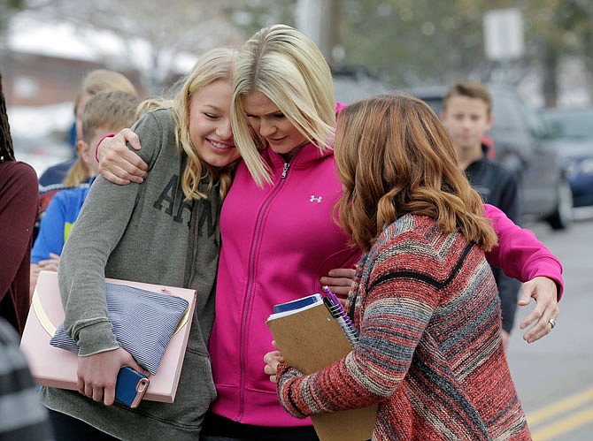 A mother greets her daughter and a friend following a lockdown at Mueller Park Junior High after a student fired a gun into the ceiling Thursday in Bountiful, Utah. Police said two fast-acting Utah parents disarmed their son in the hallway of the Utah junior high school after the teenager brought the family's shotgun and handgun to school.
