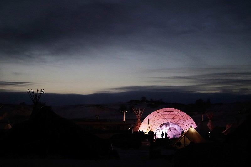 People stand outside a dome used as a community center and sleeping area at the Oceti Sakowin camp where people have gathered to protest the Dakota Access oil pipeline in Cannon Ball, N.D., Friday, Dec. 2, 2016. 
