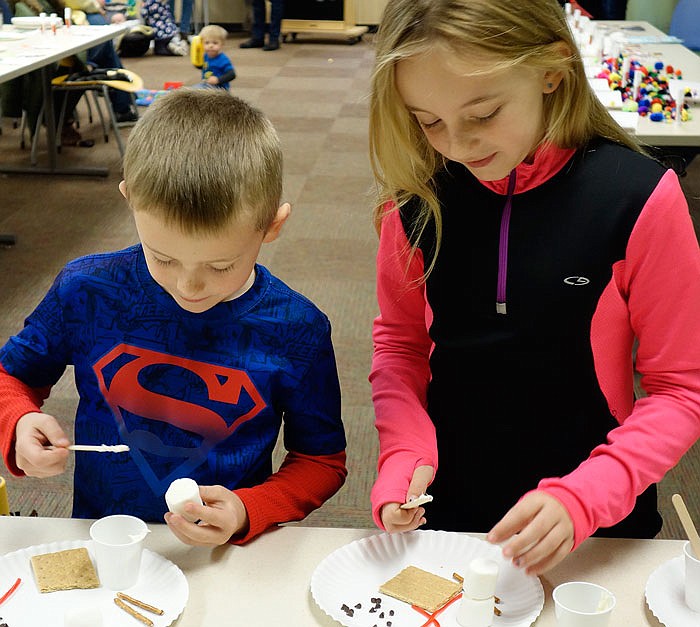 Jude Shryock, 6, and his sister, Brynn, 7, assemble edible snowmen with marshmallows, frosting and more Monday at 'Dress For A Mess' at the library in Fulton.