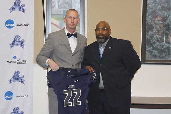 Lincoln athletic director John Moseley (left) introduces Steve Smith (right) as the Blue Tigers new head football coach Tuesday morning at a press conference held at Page Library on campus. Moseley holds a No. 22 jersey, commemorating Smith as the 22nd head coach in Lincoln football history.