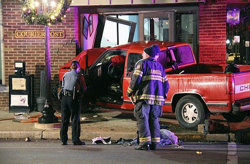 In this Monday, Dec. 5, 2016 photo, authorities survey the scene where a pickup truck slammed into the front door of the Hannibal Courier-Post building in Hannibal, Mo. The driver was treated for injuries but no employees were injured. Production of the newspaper was unaffected. (Eric Dundon/The Courier-Post via AP)