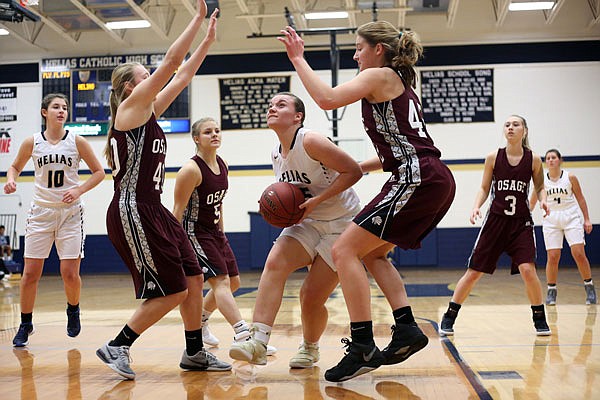 Helias forward Rachel Schulte works her way between a pair of School of the Osage defenders for a shot during Tuesday's game at Rackers Fieldhouse.