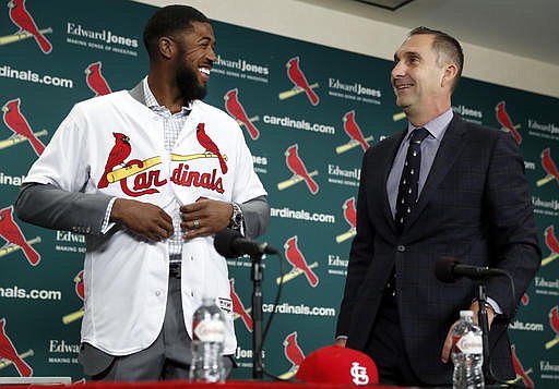 St. Louis Cardinals general manager John Mozeliak, right, watches as Dexter Fowler puts a Cardinals jersey during a baseball news conference announcing the signing of the free agent center fielder Friday, Dec. 9, 2016, in St. Louis.
