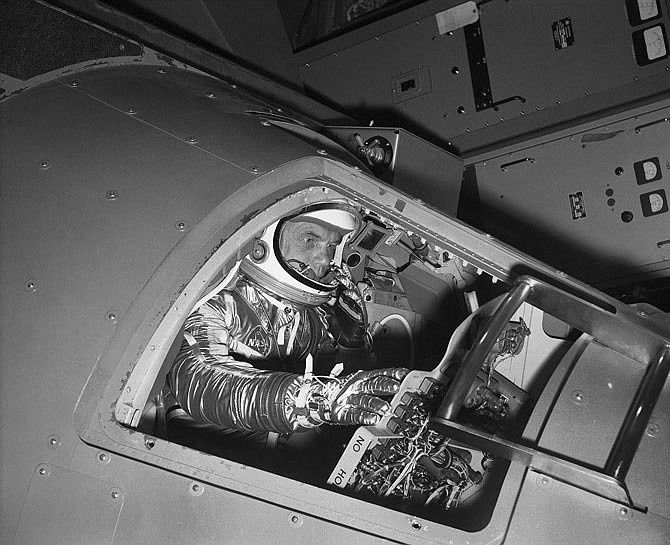 Marine Lt. Col. John Glenn reaches for controls Jan. 11, 1961, inside a Mercury capsule as he shows how the first U.S. astronaut will ride through space during a demonstration in Langley Field, Virginia. 