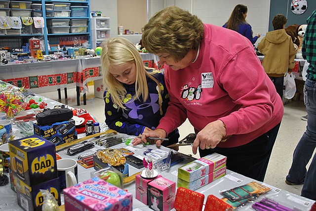 Eugene Elementary PTO volunteer Dolores Nichols assists Eugene third-grader Ava Twehus with her present selections Tuesday during the annual Santa's Workshop program, which lasts all week. 