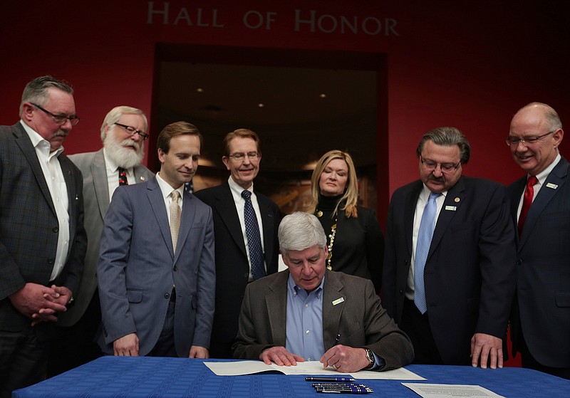 Michigan Gov. Rick Snyder signs legislation that establishes comprehensive regulations for the testing, use and eventual sale of autonomous vehicle technology at the Automotive Hall of Fame in Dearborn, Mich., on Friday Dec. 9, 2016.   The package of bills signed into law Friday comes with few specific state regulations and leaves many decisions up to automakers and companies like Google and Uber. It also allows automakers and tech companies to run autonomous taxi services and permits test parades of self-driving tractor-trailers as long as humans are in each truck.  