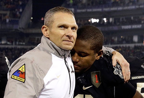 In this Dec. 13, 2014, file photo, Army head coach Jeff Monken (left) embraces running back Larry Dixon after losing 17-10 to Navy in Baltimore. The 117th Army-Navy game is today in Baltimore.