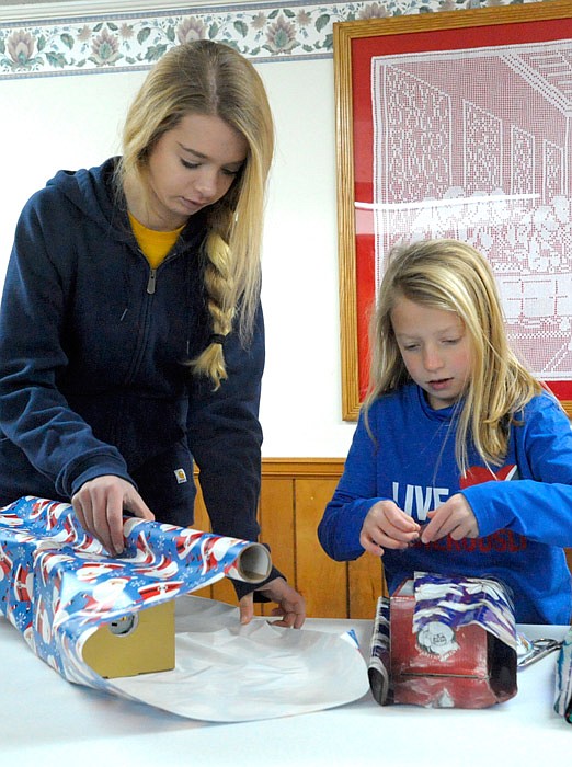 Trinity Lutheran Church of Russellville youth Hannah Mehmert and Kate Oligschlaeger wrap gifts for children at the Santa's Workshop Giveaway Saturday, Dec. 10, 2016.