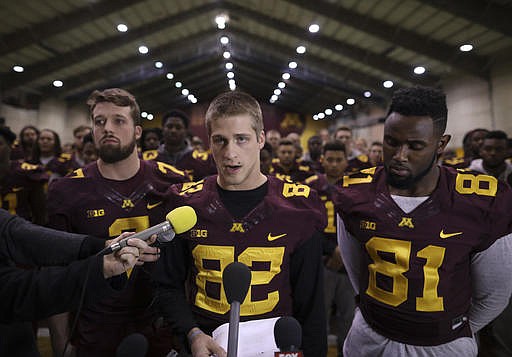 In this Dec. 15, 2016, file photo, University of Minnesota wide receiver Drew Wolitarsky, flanked by quarterback Mitch Leidner, left, and tight end Duke Anyanwu stands in front of other team members as he reads a statement on behalf of the players in the Nagurski Football Complex in Minneapolis, Minn. The University of Minnesota football team will play in the Holiday Bowl, reversing a threat to boycott the game because of the suspension of 10 players accused of sexual assault. The players made the announcement at a news conference Saturday, Dec. 17, after a group of seniors from the team met with the board of regents, university President Eric Kaler and athletic director Mark Coyle on Friday night. (Jeff Wheeler/Star Tribune via AP, File)
