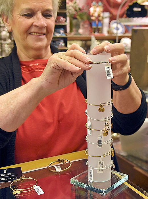 Gen Brandt restocks Alex and Ani bracelets at Southbank Gift Company. Shoppers were out Monday looking for after-Christmas deals.