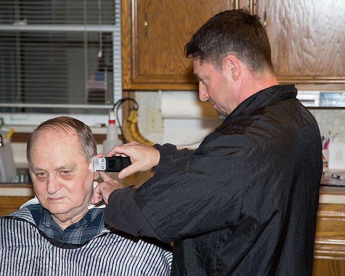 Local barber Mike Tanner cuts the hair of John Bollinger at Bollinger's home in Jefferson City.