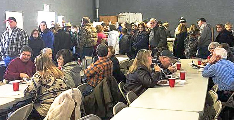 At the Travis Peck benefit fundraiser, a long line of people wait for meals and check out the many items donated for the silent auction. About 700 meals were served, more than double what was expected.