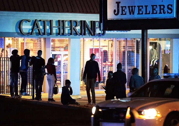 Police officers continue to patrol the area as people linger in the parking lots around Oak Court Mall after the mall was closed due to a disturbance Monday in Memphis, Tennessee. 