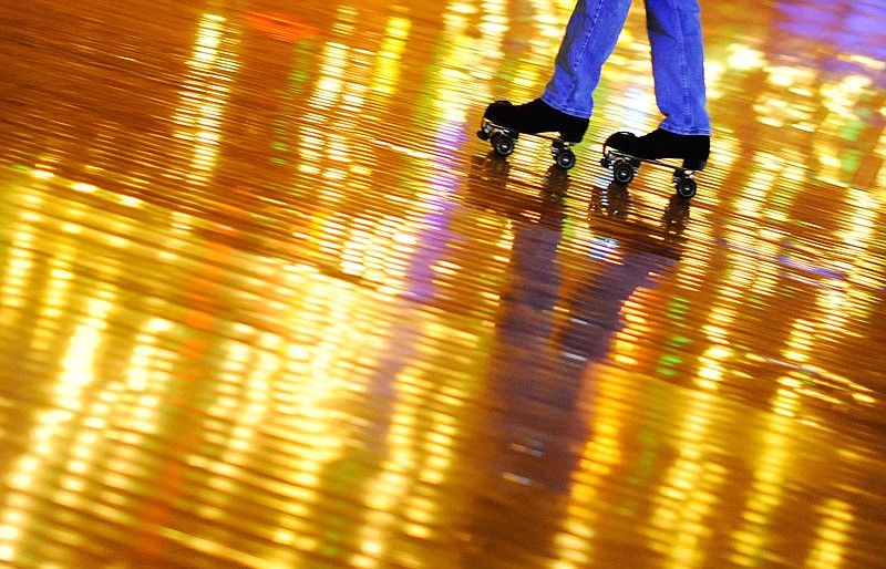 A skater glides backwards across the rink as it reflects the golden strobe lights overhead at Sk8 Zone in Jefferson City.