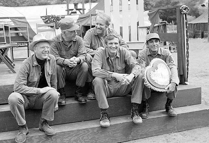 In this Sept. 15, 1982 photo, cast members of the television series "M*A*S*H" from left, William Christopher, Harry Morgan, Mike Farrell, Alan Alda, and Jamie Farr, take a break on the set during taping in Los Angeles.