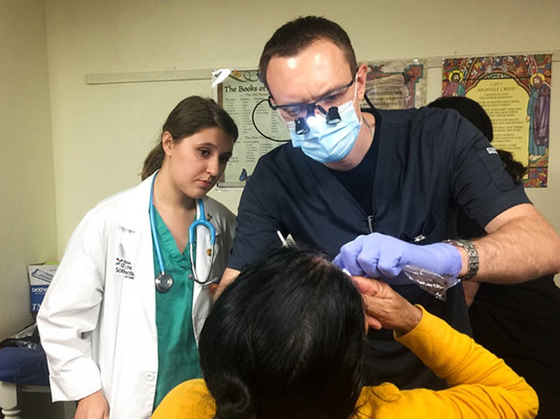Third-year dental student Alex Dolbik checks the oral health of a patient at the Refugee Health Clinic in San Antonio.