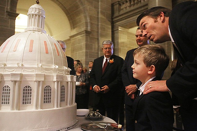 House Speaker Todd Richardson, right, stands Wednesday with his son Sawyer Richardson, 8, during the Capitol Capstone anniversary celebration at the Capitol. The Missouri State Capitol Commission hosted a celebration of the centennial of the laying of the capstone of the Capitol with a "dome" cake baked by Edith Hall. 