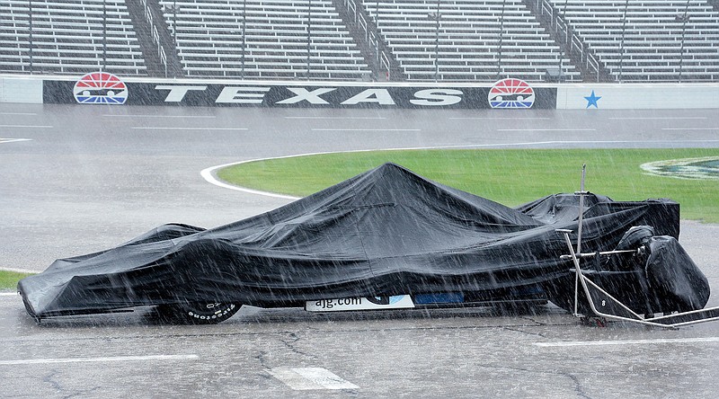 In this June 12, 2016, file photo, the race car of Max Chilton, from England, is covered by a tarp during a thunderstorm which stopped an IndyCar auto race at Texas Motor Speedway, in Fort Worth, Texas. Texas Motor Speedway is going to completely repave its 1 1/2-mile track and reduce the high banking in the first and second turns. The project announced Friday, Jan. 6, 2017, comes after both NASCAR weekends and the IndyCar race at Texas last year were hampered by rain.