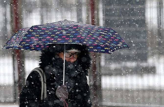 A woman shelters from snowfall with an umbrella as she walks through the street Monday on a cold winter day in Belgrade, Serbia.