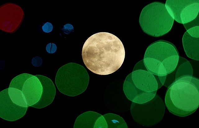 A nearly-full moon is seen in December 2015 among Christmas lights at a holiday display near Lenexa, Kansas. Israeli scientists reported Monday that rather than one giant impact that knocked off part of early Earth and created the moon, a number of smaller collisions may have produced lots of mini-moons. And those mini-moons, over millions of years, may have clumped together to make one large one.