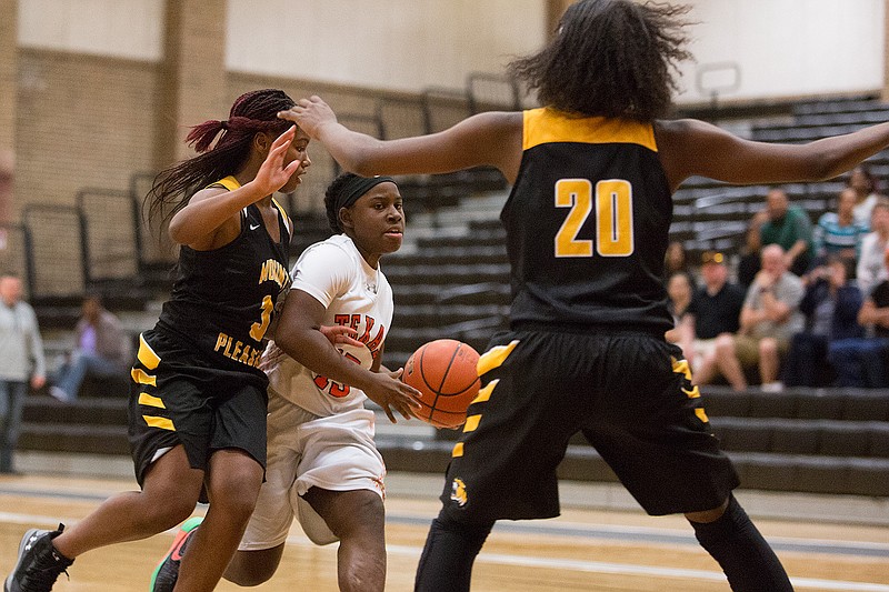 Texas High's Mia Wilson drives the lane as Mount Pleasant's Keke Craddock and Sakaria Grant defend during Tuesday night's game in Texarkana, Texas. 