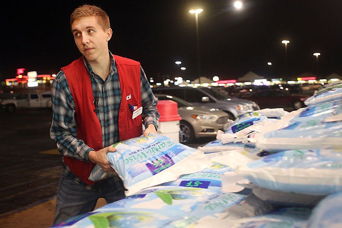 Employee Drew Owens moves a bag of salt for a patron Wednesday at Westlake ACE Hardware on Missouri Boulevard. Customers stocked up on salt and other winter merchandise in preparation for this weekend's winter weather forecast.