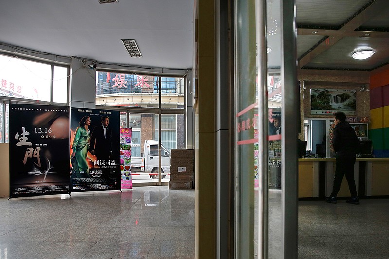 In this Dec. 12, 2016 photo, a man checks on movies at a ticket counter of the Digital Cinema in Zhuolu county in north China's Hebei province. The brightly-decorated 3-D cinema in this town outside Beijing is showing the latest Chinese and Hollywood films, to row after row of empty red seats. So few people come to watch films here that the theater manager rents out the halls to travelling sales companies or music teachers. 