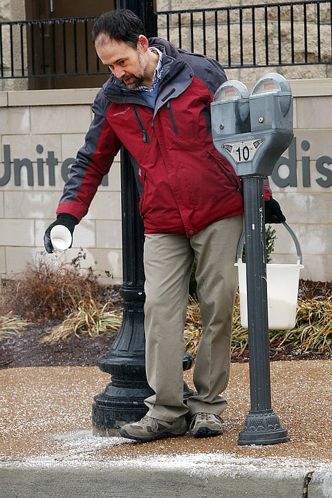 Pastor Daniel Hilty thoroughly salts the sidewalk Saturday outside of the First United Methodist Church. Although there was a midday lull in the inclement weather, more ice was expected to accumulate overnight.