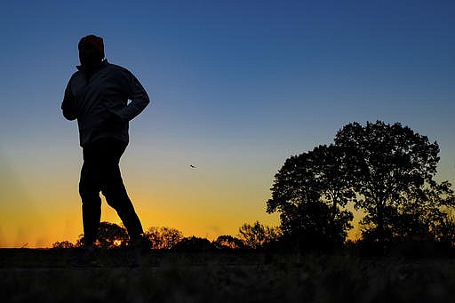 In this Tuesday, Nov. 22, 2016 file photo, a runner is silhouetted against the sunrise on his early morning workout near Arlington National Cemetery in Arlington, Va., across the Potomac River from the nation's capital.