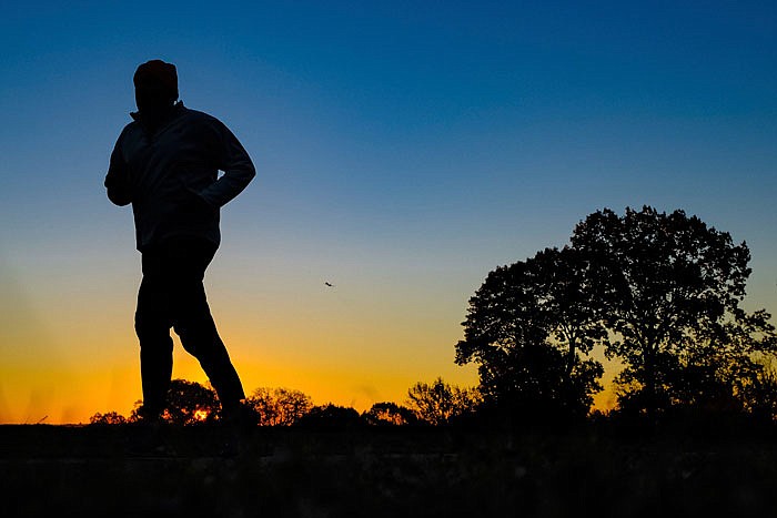 A runner is silhouetted against the sunrise on his early morning workout near Arlington National Cemetery in Arlington, Virginia, across the Potomac River from the nation's capital. 