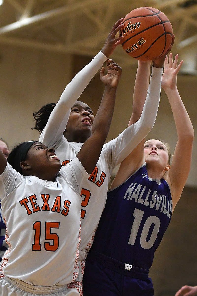 Texas High's Unique McBride, center, and Mia Wilson battle for a rebound against Hallsville's Hanna Poteet on Tuesday at the Tiger Center in Texarkana, Texas. 
