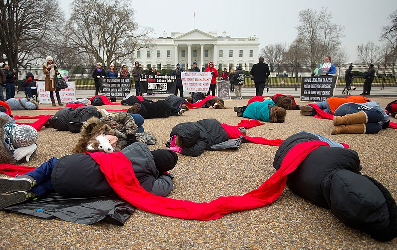 In a Wednesday, Jan. 21, 2015, file photo, anti-abortion rights activists are connected with a red piece of cloth as they stage a 'die-in' in front of the White House in Washington. Even as the 2016 election outcome intensifies America's abortion debate, a comprehensive new survey released Tuesday, Jan. 17, 2017 by the Guttmacher Institute finds the annual number of abortions in the U.S has dropped to well under 1 million, the lowest level since 1974. 