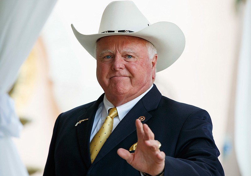 In this Dec. 30, 2016, file photo, Texas Agriculture Commissioner Sid Miller waves as he arrives at Mar-a-Lago to meet with President-elect Donald Trump's transition team in Palm Beach, Fla. A claim by Miller that "illegal aliens" attacked a hunting party in remote West Texas was criticized Monday, Jan 16, 2017, by the local sheriff who says the hunters fired on one another. Miller said in a recent Facebook post that the attack is another reason why a wall must be built to secure the Texas border. 