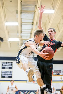Landon Harrison of Helias looks to pass against the defense of Charlie Wehmeyer of Jefferson City during Tuesday night's game at Rackers Fieldhouse