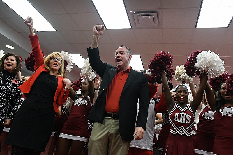 New Texarkana, Ark., School District head football coach and athletic director Barry Norton, center, learns how to 'call the hogs' with the help of TASD Superintendent Dr. Becky Kesler, left, and the Arkansas High School cheerleaders after a press conference announcing the appointment of Norton on Wednesday at The TASD Administration Building. 