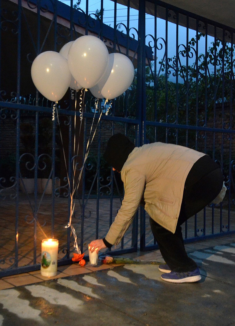 A woman places a candle at the entrance of the American School of the Northeast, after a school shooting in Monterrey, Mexico, Wednesday, Jan. 18, 2017. A 15-year-old student opened fire with a gun on Wednesday, hitting a teacher and two other students in the head before killing himself.