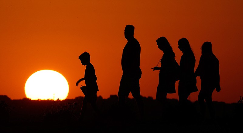 In this July 21, 2016, file photo, the sun sets beyond visitors to Liberty Memorial on Thursday, July 21, 2016, as the temperature hovers around 100 degrees in Kansas City, Mo. For the third straight year, Earth set a record for the hottest year, NOAA and NASA announced. NASA says 2016 was warmer than 2015 - by a lot. It's mostly global warming with a little assist from the now-gone El Nino. 