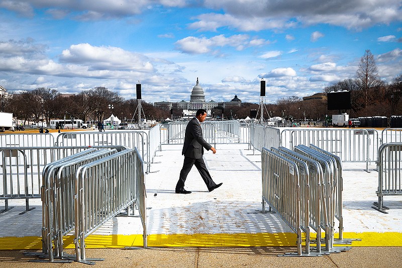 A pedestrian walks through the National Mall in Washington, Wednesday, Jan. 18, 2017, with the Capitol in the background, as work continues in preparation for Friday's presidential inauguration. 