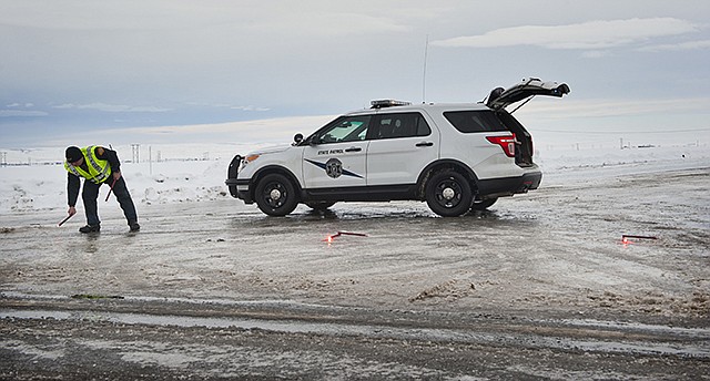 Washington State Patrol Trooper Wes Cook sets up flares Wednesday morning to close Harvey Shaw Road just north of Walla Walla. Freezing rain, ice and fallen trees forced the closure of highways and roads in Oregon and Washington on Wednesday.