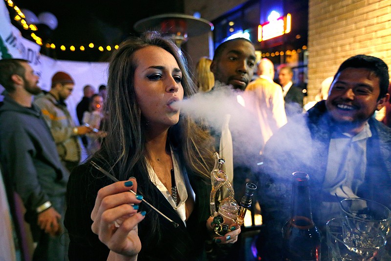 In this Dec. 31, 2013, file photo, partygoers smoke marijuana during a Prohibition-era themed New Year's Eve party at a bar in Denver, celebrating the start of retail pot sales. Denver is starting work on becoming the first city in the nation to allow marijuana clubs and public pot use in places like restaurants, yoga studios and art galleries. Voters narrowly approved the "social use" measure last November.